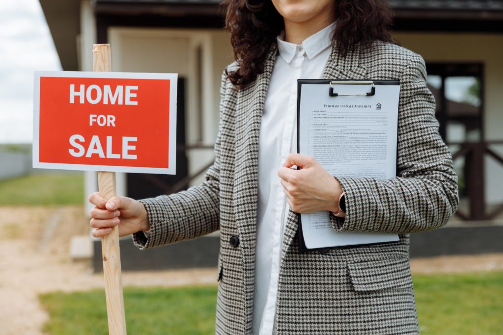 a photo of a realtor holding a for sale sign and a purchase contract