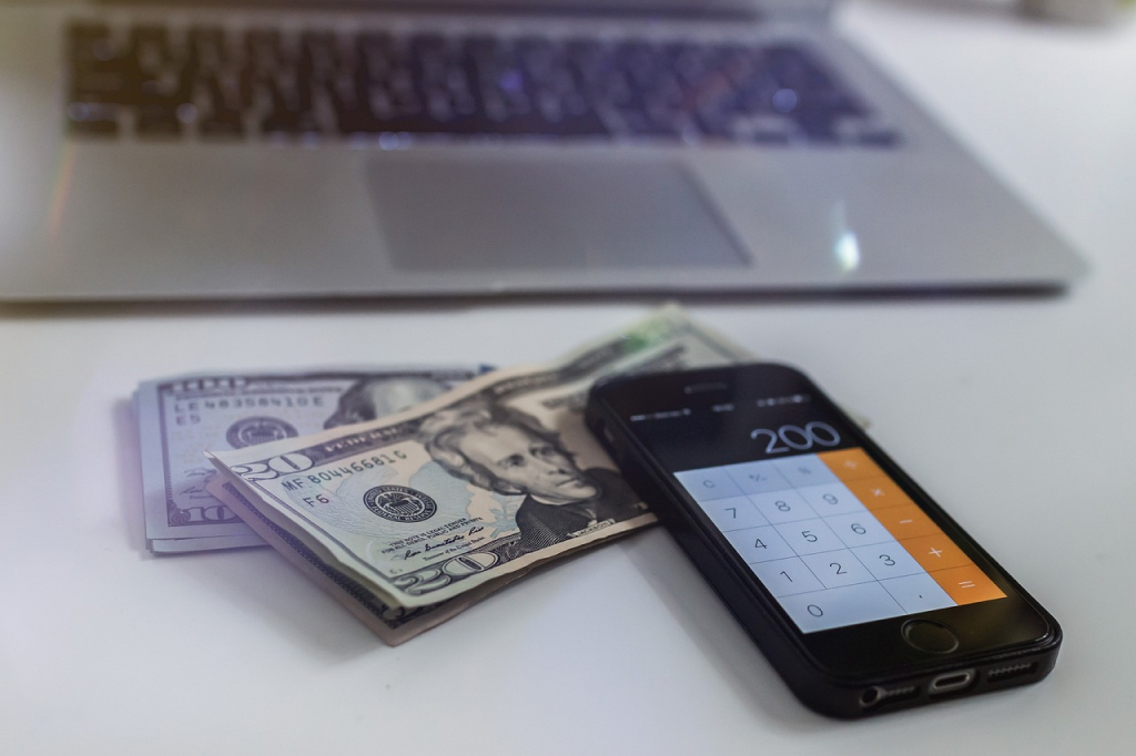 Image of a cash and a phone on a desk for the california probate fees Blog Article